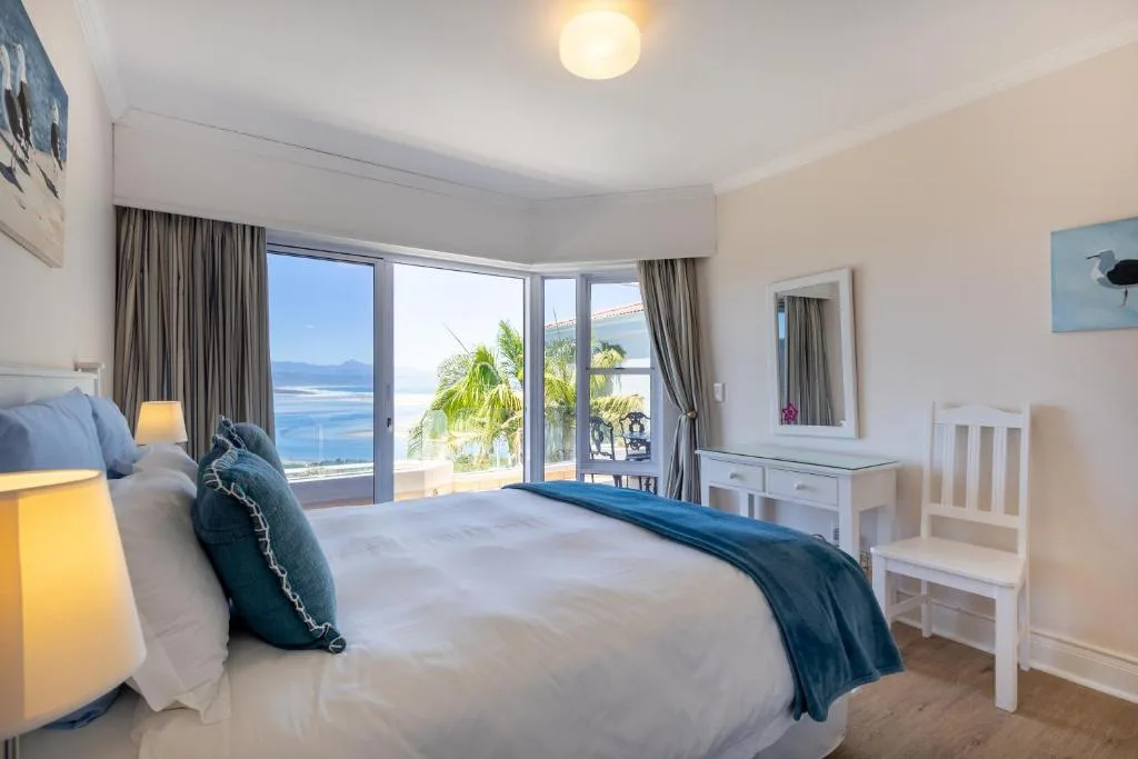Spacious bedroom with ocean view through large sliding doors and palm trees