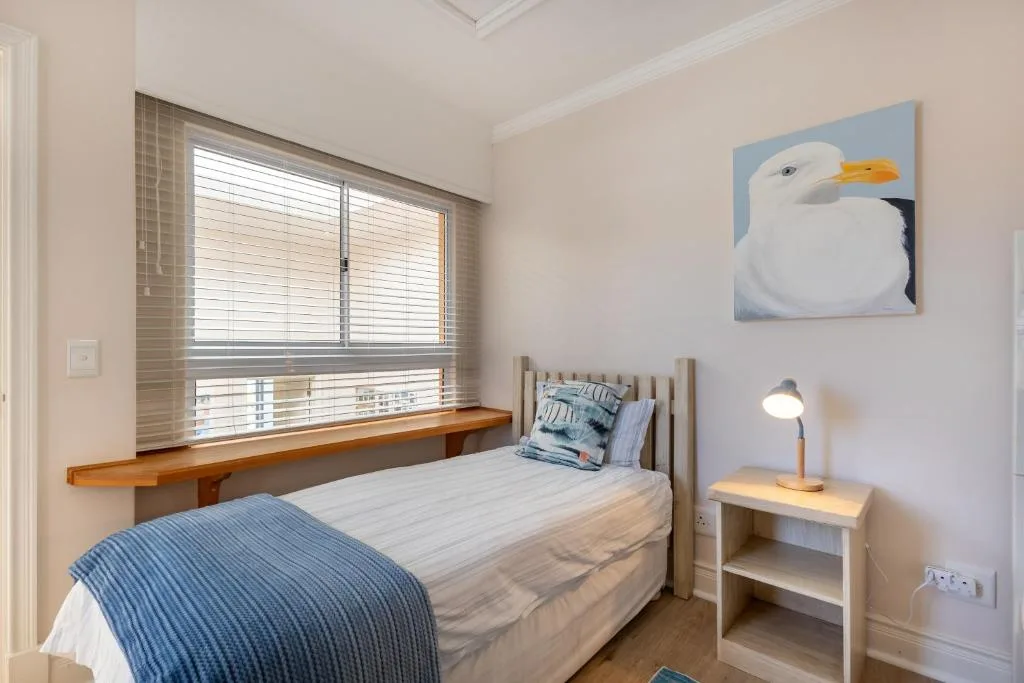 Bright bedroom with single bed, window seat, and seagull artwork