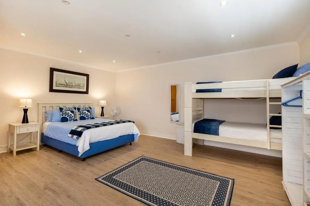 Spacious bedroom with queen bed and white bunk beds, nautical decor