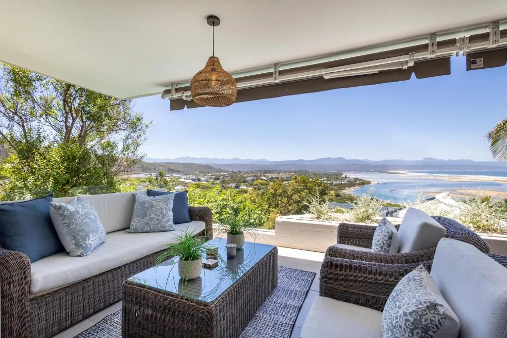 Covered outdoor seating area with woven pendant light and panoramic lagoon views