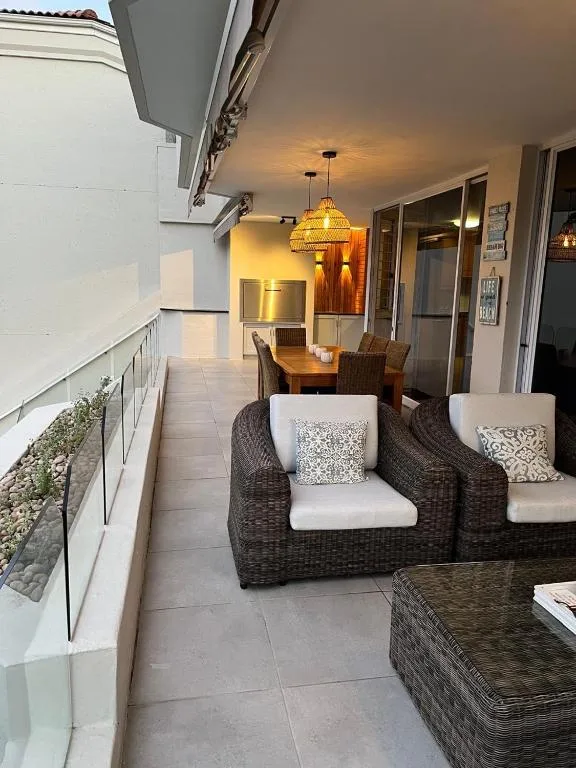 Covered patio with wicker seating, dining table, and warm pendant lighting