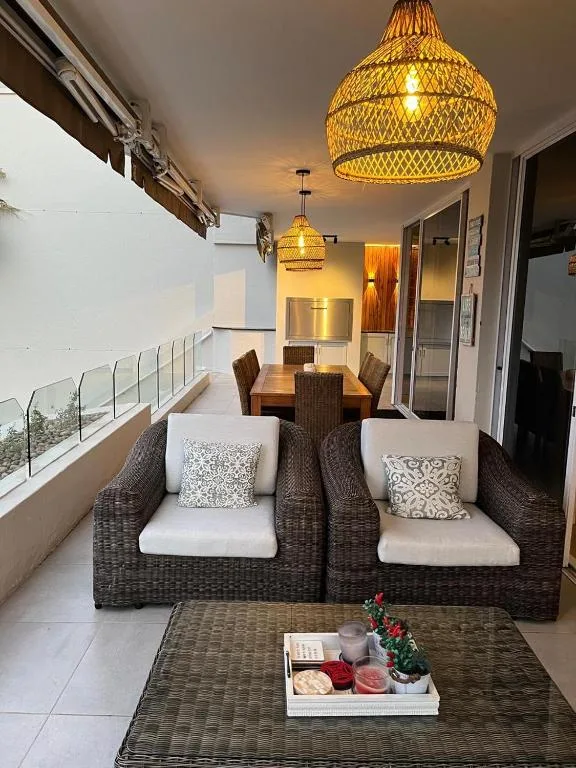 Covered patio area with wicker seating, pendant lights, and ocean view