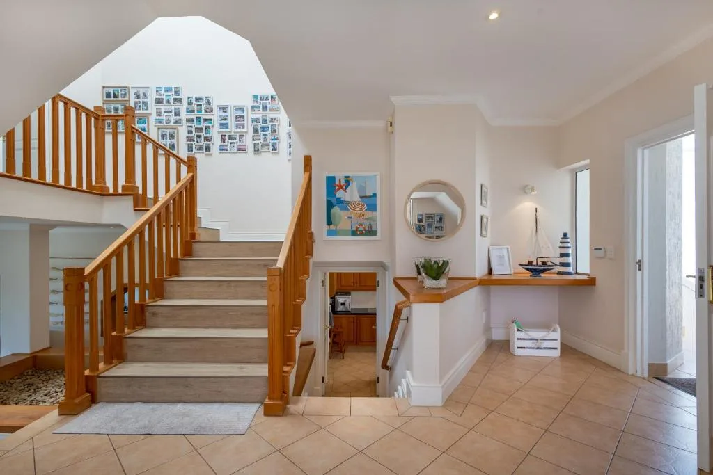 Bright entrance hall with wooden staircase and decorative wall shelving