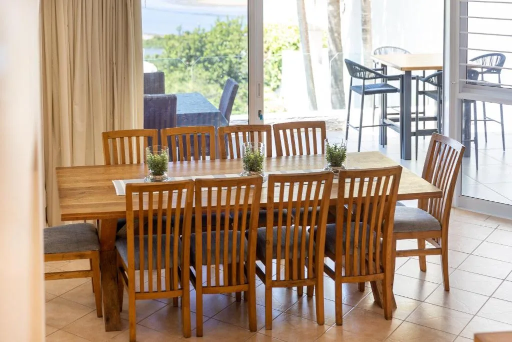 Wooden dining table with eight chairs, opening to deck and garden views