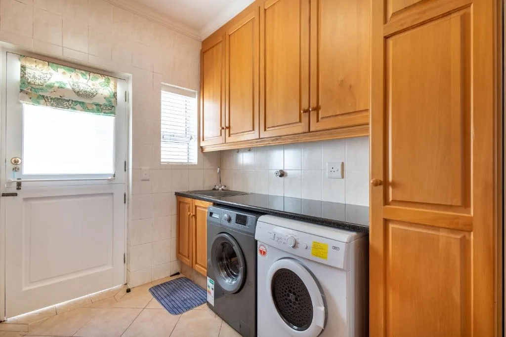 Compact kitchen with wooden cabinetry, washing machine, and dryer
