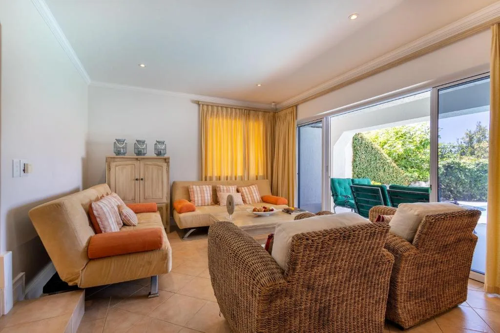 Spacious lounge with wicker chairs, sofa, and garden views through sliding doors