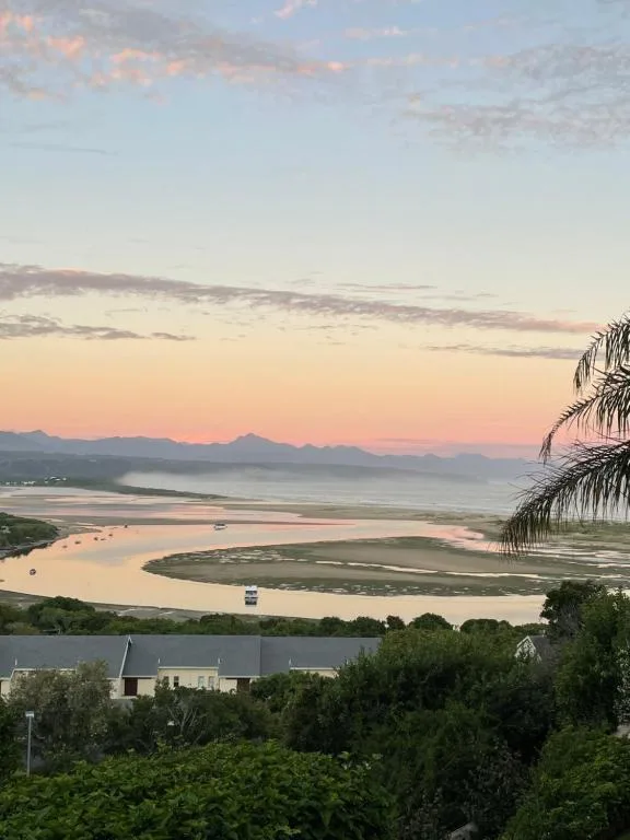 Sunset over Plett lagoon with distant mountains and palm frond
