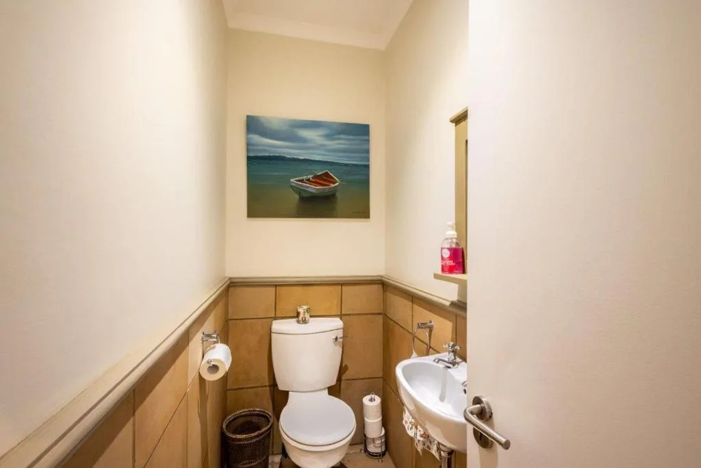 Guest bathroom with toilet, sink, and wooden wall paneling