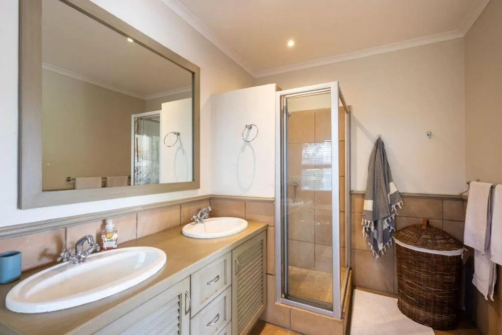 Spacious bathroom with dual vanity sinks, large mirror, and glass shower enclosure