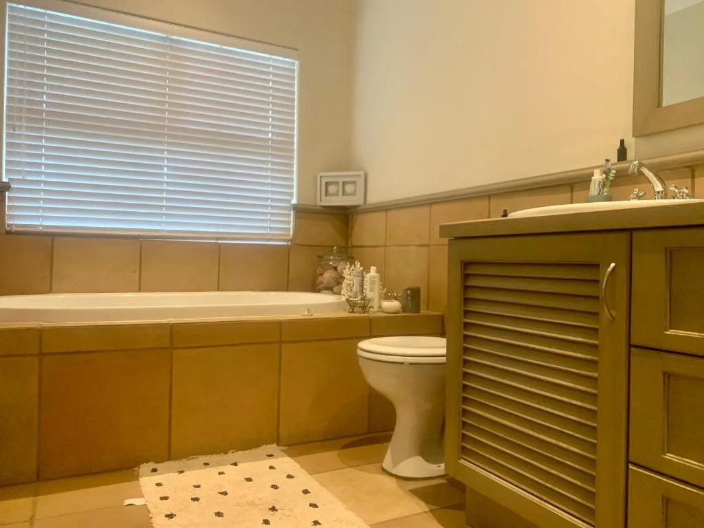 Warm-toned bathroom with soaking tub, toilet, and wooden cabinetry