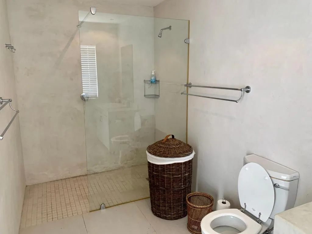 Modern bathroom with walk-in shower, toilet, and wicker storage baskets