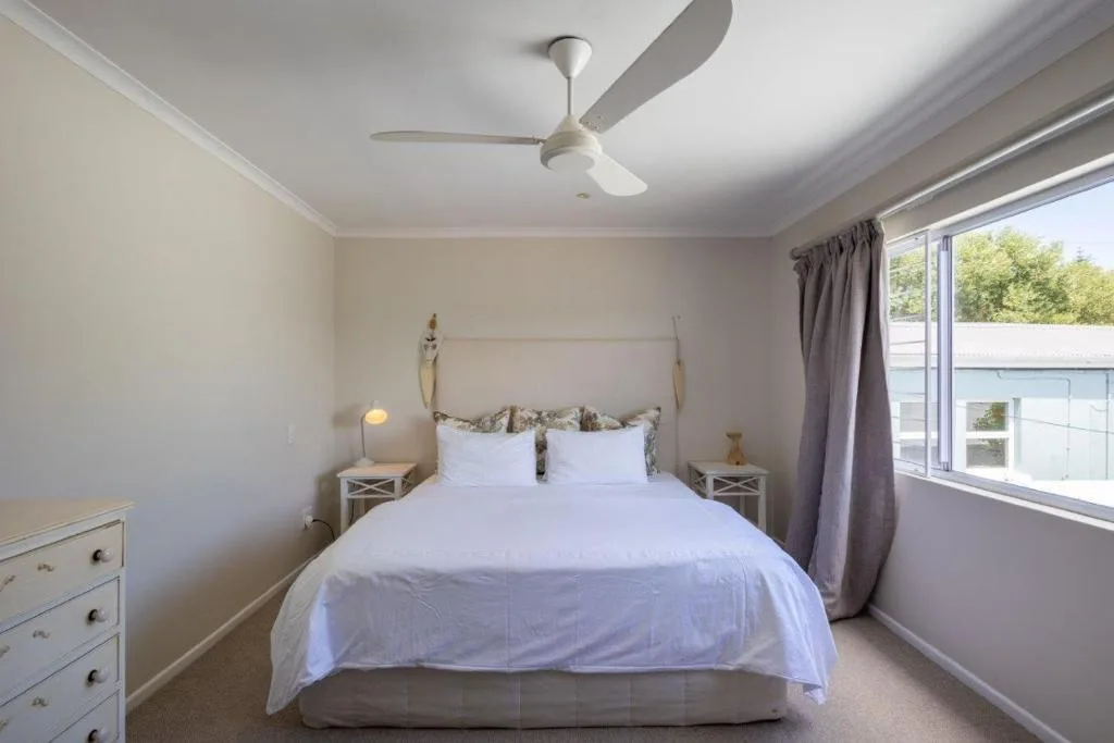 Bright bedroom with queen bed, white linens, and modern ceiling fan