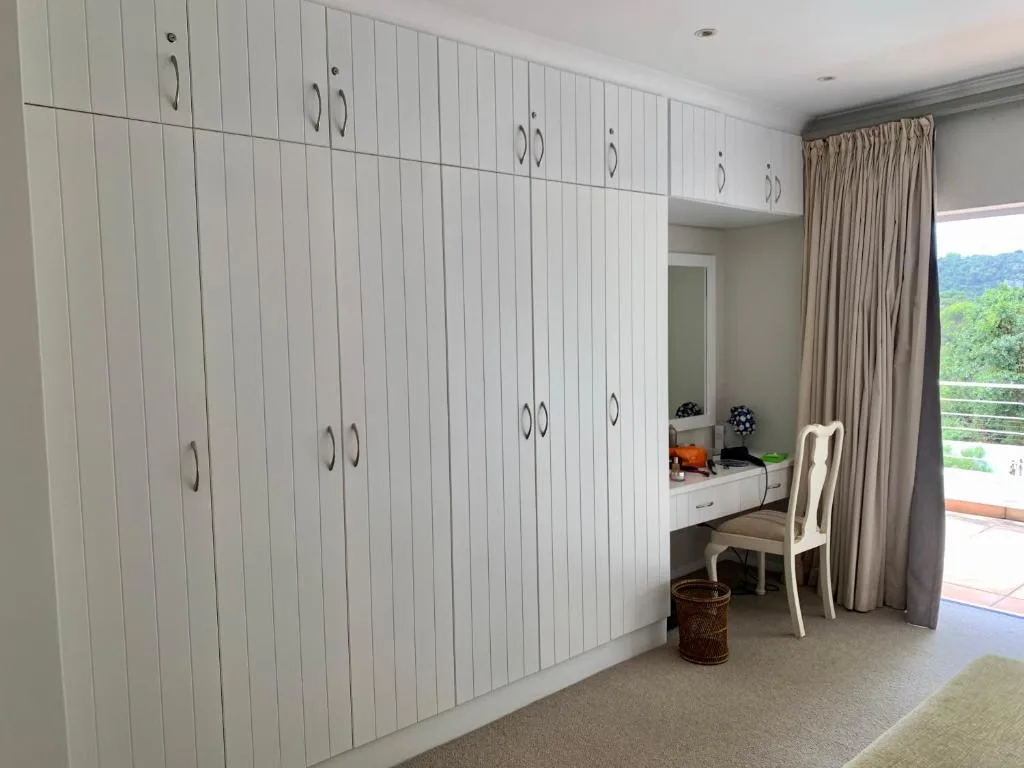 Spacious bedroom with built-in white cabinetry and mountain views through glass doors