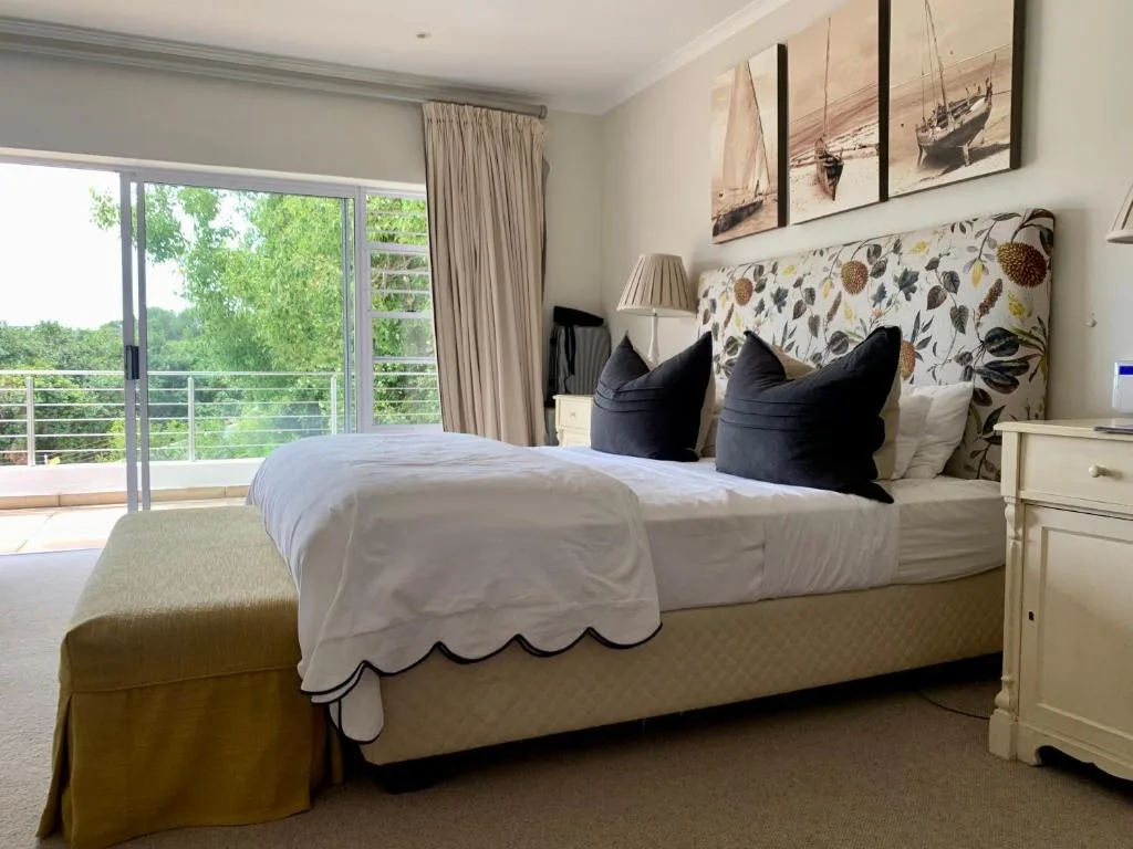 Bright bedroom with queen bed, patterned headboard, and sliding doors overlooking garden