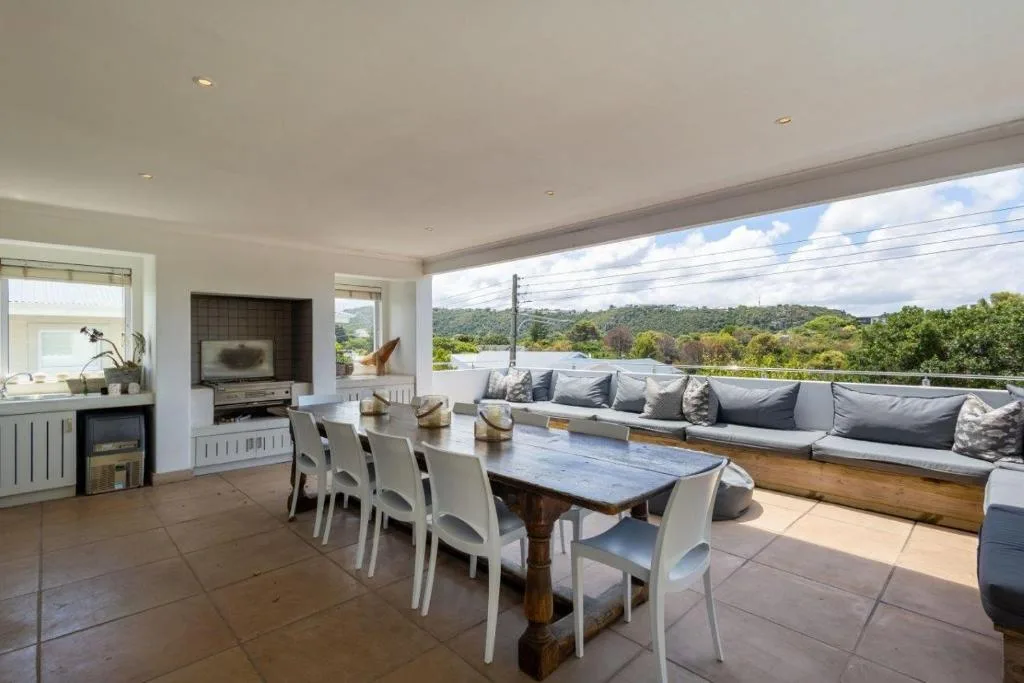 Spacious outdoor deck with dining table and lounge seating overlooking green landscape
