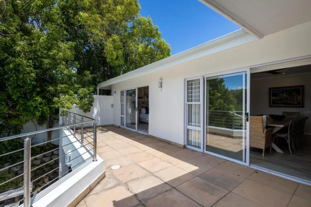 Modern paved deck with metal railings and sliding glass doors opening into the house