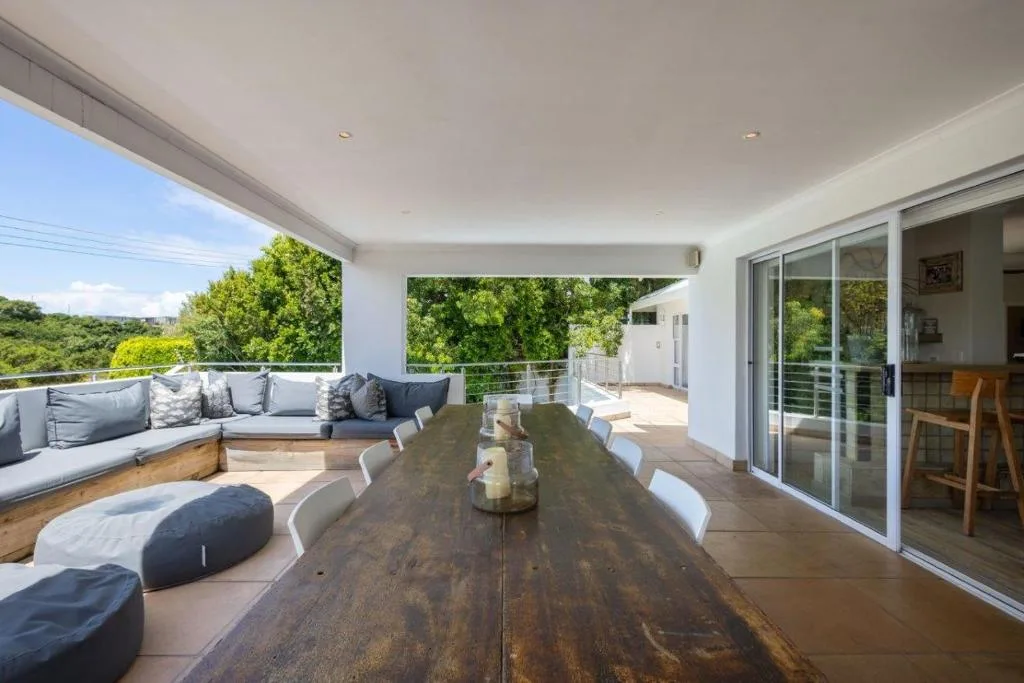 Spacious covered deck with dining table, lounge seating, and garden views