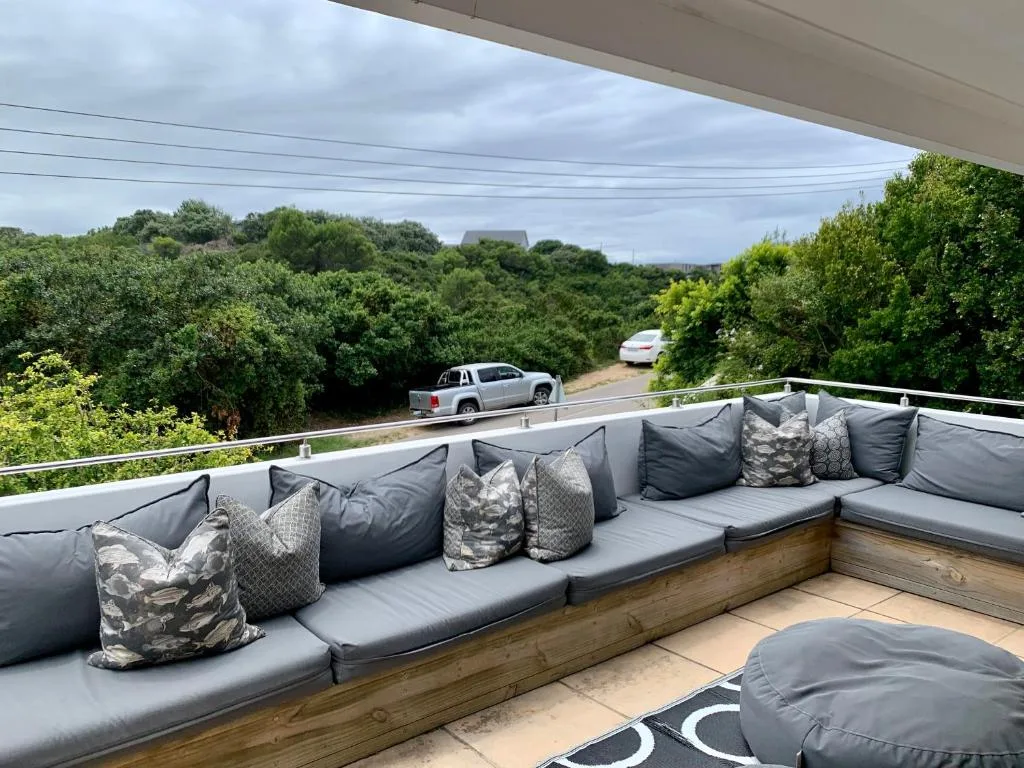 Built-in outdoor seating with cushions overlooking lush garden and driveway