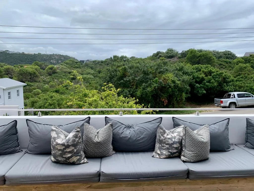 Outdoor deck with grey upholstered seating and patterned pillows overlooking lush garden