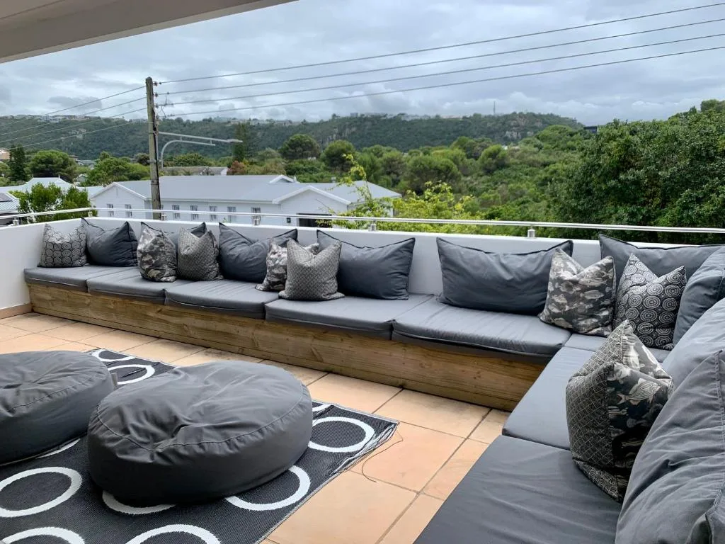 Spacious outdoor deck with built-in seating, cushions, and garden views