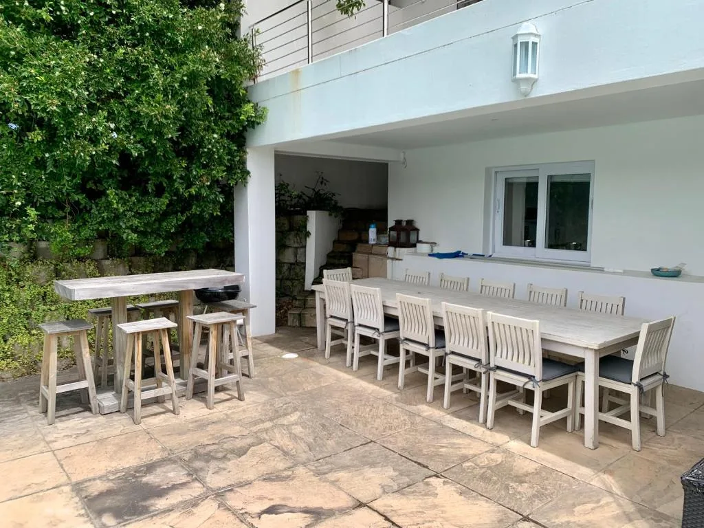 Outdoor patio with long dining table, bar seating, and ivy-covered walls