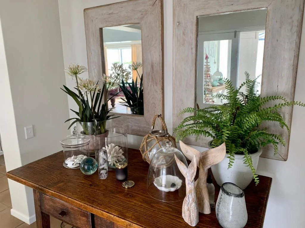 Wooden console table with decorative plants, mirrors, and home accessories