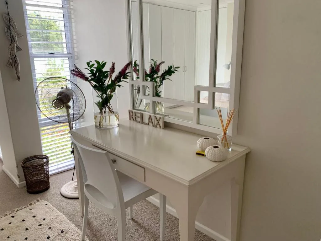 Bright bedroom vanity with mirror, flowers, and relaxation decor displayed