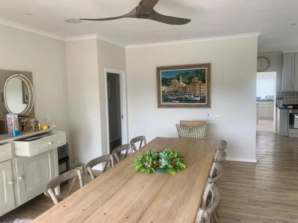 Spacious dining room with wooden table and coastal artwork on walls