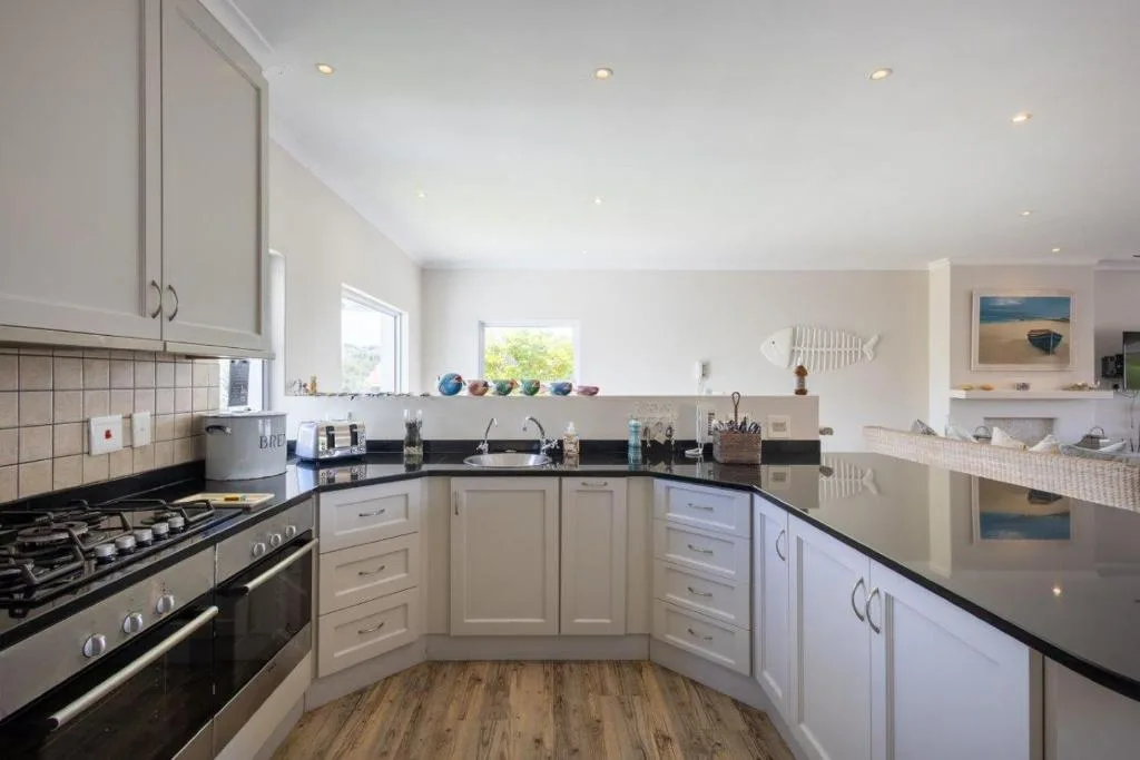 Modern kitchen with white cabinetry, black countertops, and stainless steel appliances