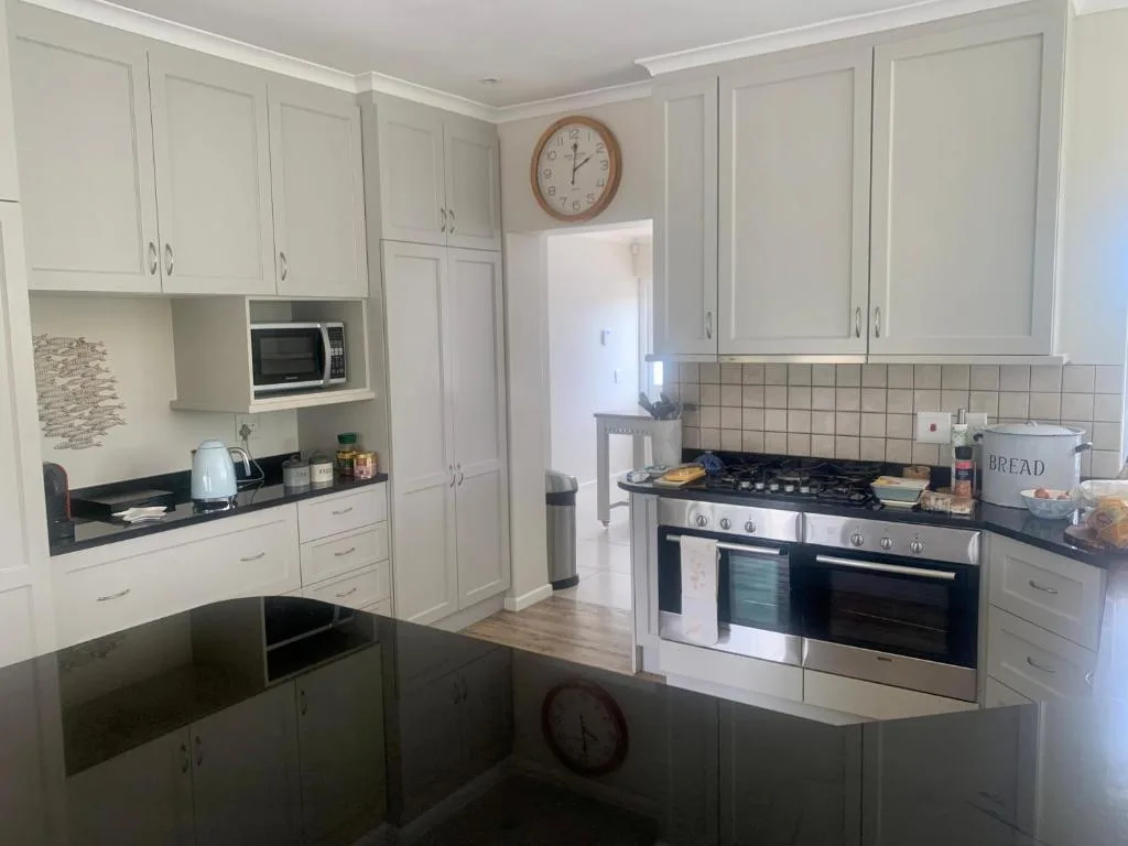 Modern kitchen with white cabinetry, black countertops, and stainless steel appliances