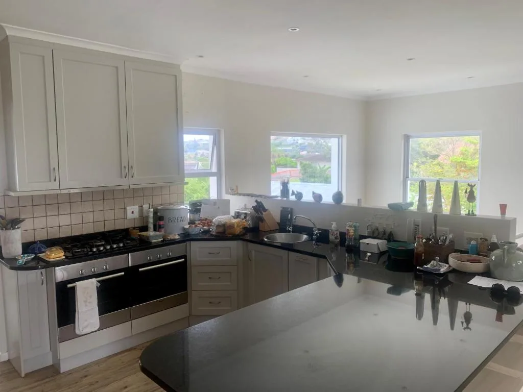 Modern kitchen with black stove, cream cabinetry, and garden views through windows