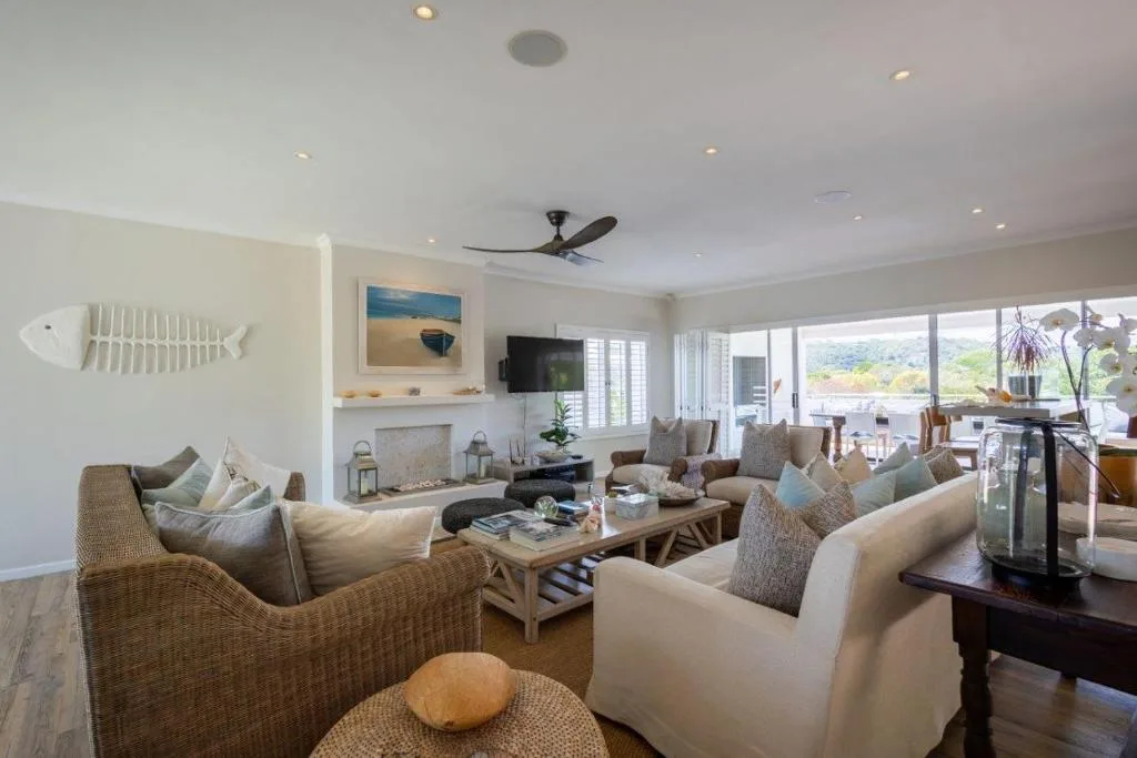 Spacious living room with woven chairs, fireplace, and garden views
