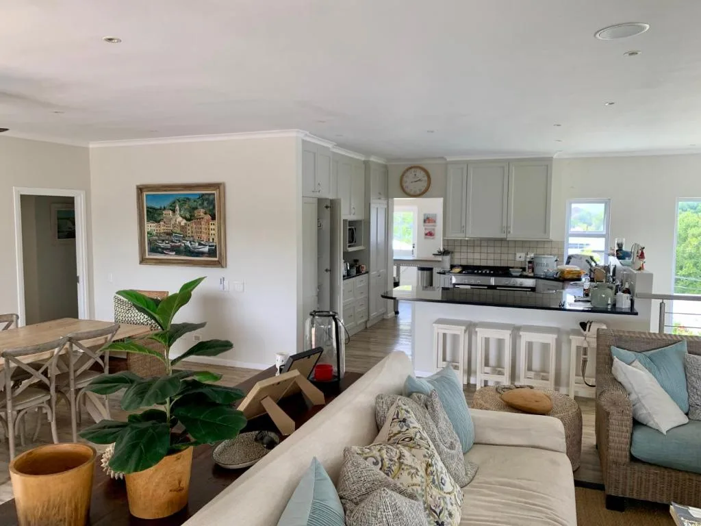 Open-plan living area with cream sofa, kitchen island, and dining table visible