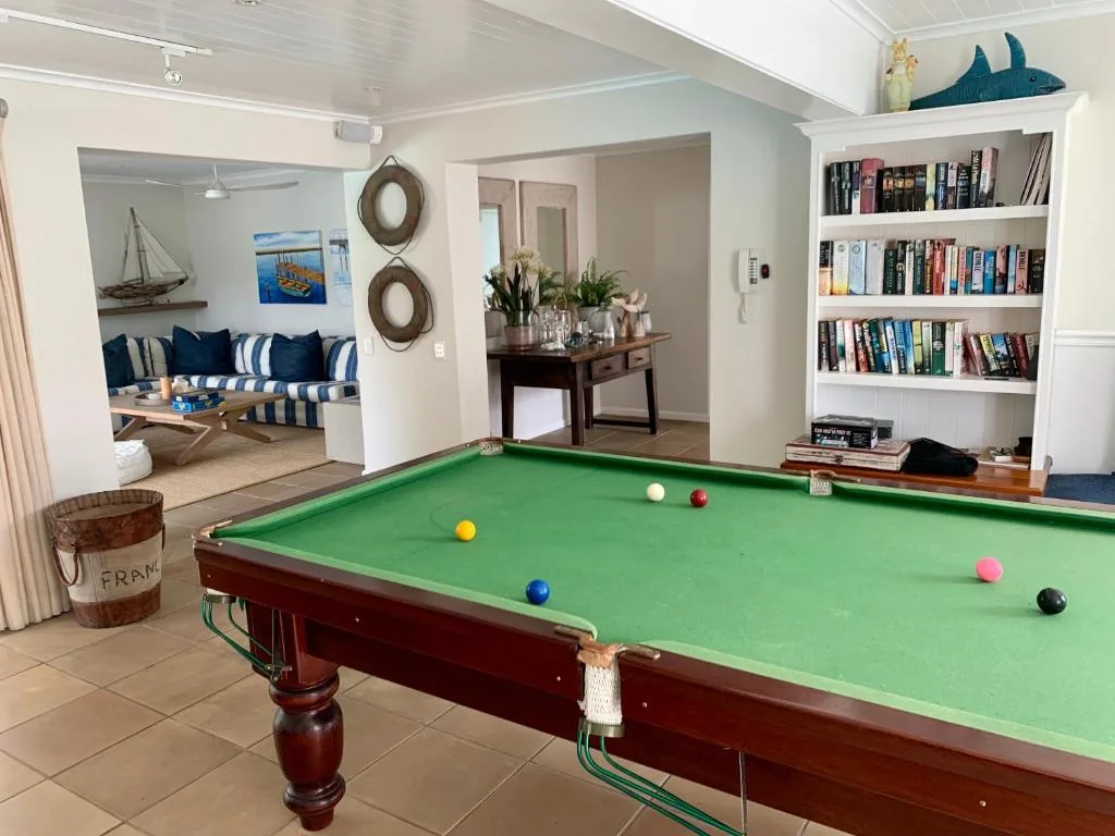 Open-plan lounge with pool table, bookshelf, and coastal-themed seating area