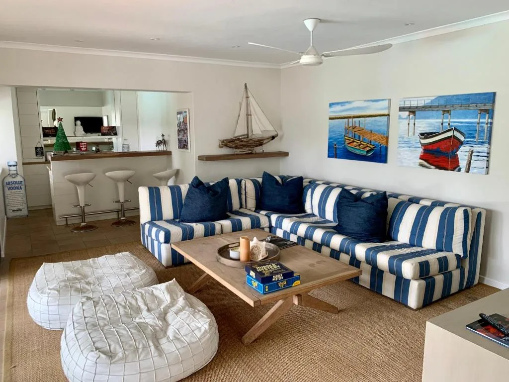 Spacious lounge with striped blue and white sofa, nautical artwork, and ocean views