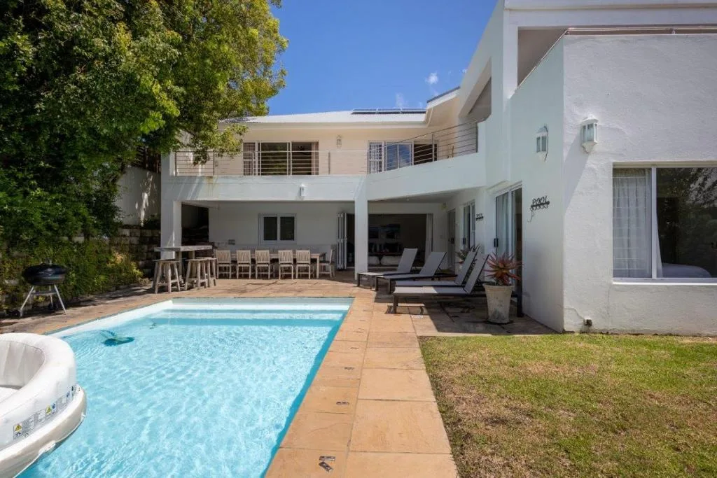 Sparkling swimming pool with wooden deck and modern white house