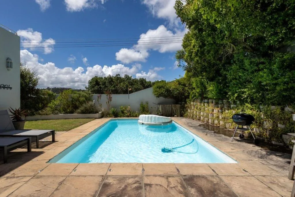 Rectangular swimming pool with loungers and braai area in fenced garden