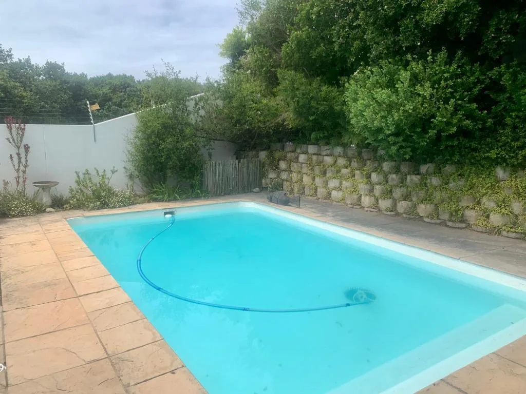 Bright turquoise swimming pool with terracotta paving and lush garden surroundings