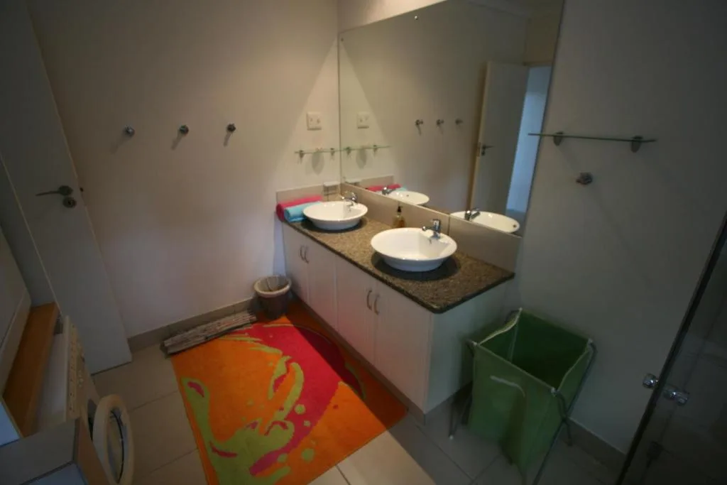 Dual vanity bathroom with stone countertops and colorful floor mat