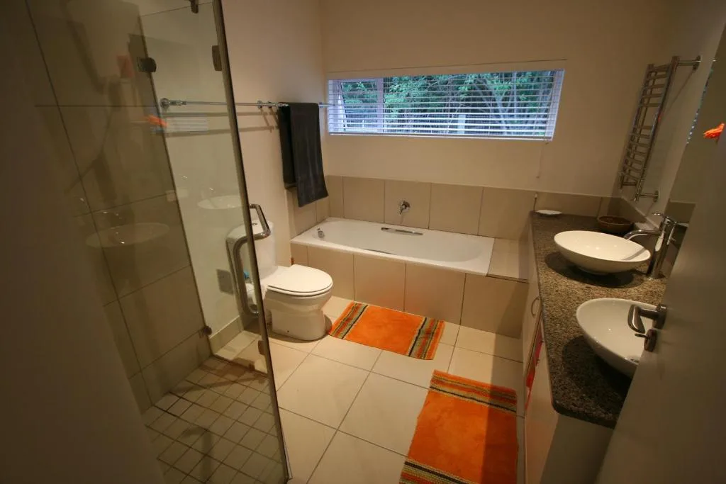Modern bathroom with walk-in shower, bathtub, dual vanities, and natural light