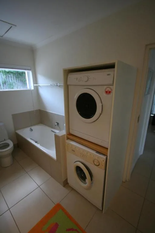 Bathroom with stacked washing machines, bathtub, and toilet fixture