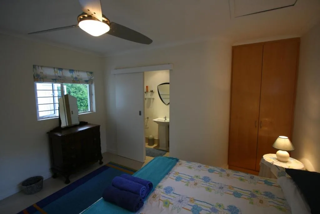 Bedroom with double bed, ceiling fan, wooden wardrobe, and ensuite bathroom visible