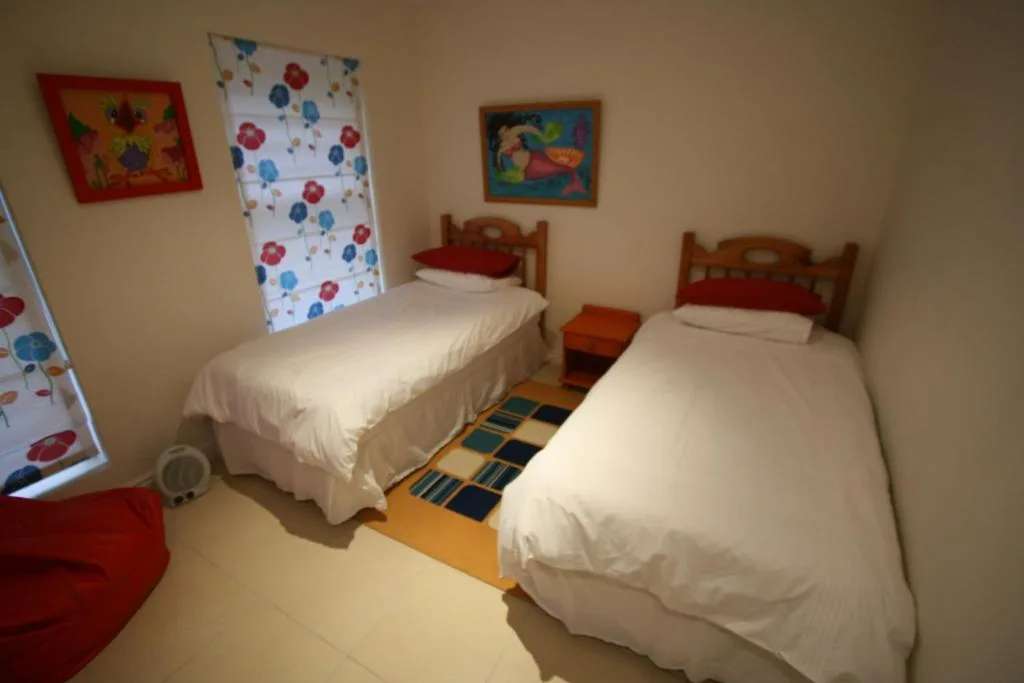 Twin bedroom with colorful artwork, wooden bed frames, and white bedding