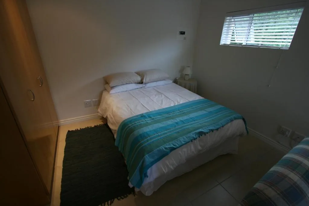 Clean bedroom with double bed, white pillows, and turquoise throw blanket