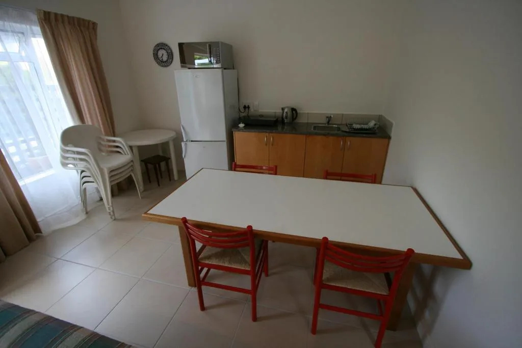Dining table with red chairs and kitchen area visible in background