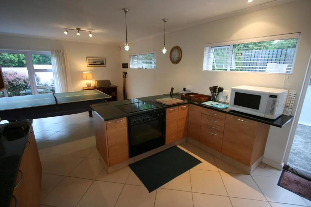Modern kitchen with wooden cabinetry, black countertops, and stainless steel appliances