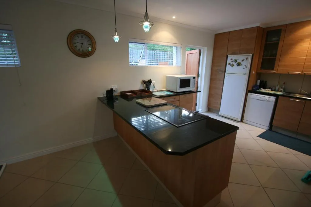 Modern kitchen with wooden cabinetry, black countertop island, and stainless steel appliances