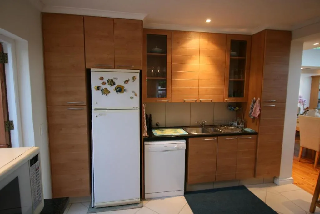 Modern kitchen with wood cabinetry, white refrigerator, and stainless steel appliances