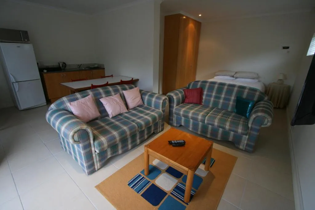 Living room with two upholstered sofas, wooden coffee table, and kitchen area visible