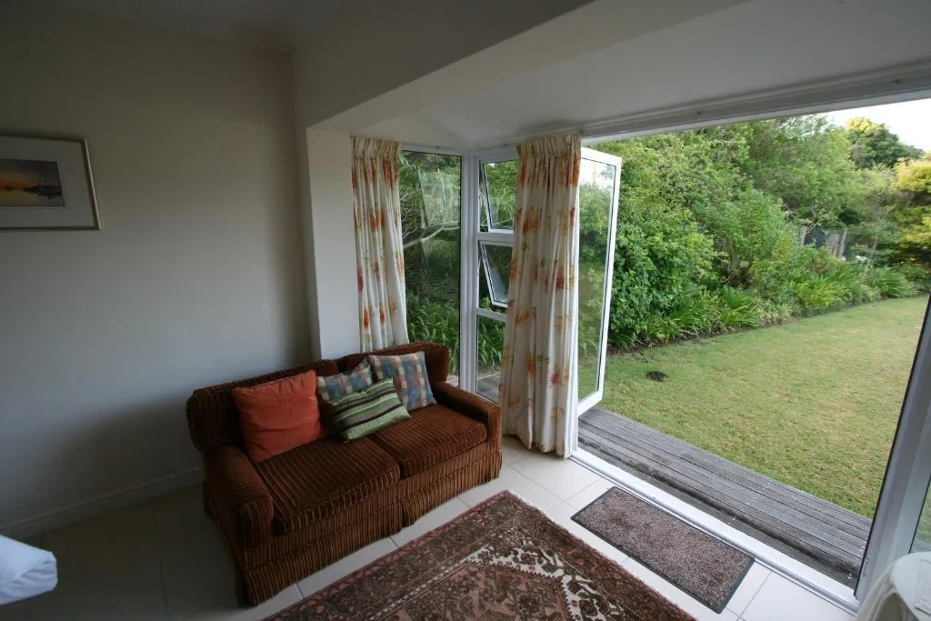 Comfortable brown sofa with colorful pillows overlooking manicured garden lawn